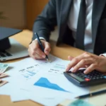 Young Australian graduate using calculator to pay off student debt faster with financial planning documents and HELP debt paperwork