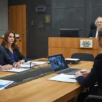 Self-represented Australian individuals presenting evidence at a tribunal hearing with documents, photos, and a tribunal member present.