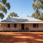 Modern Australian barndominium with steel-frame construction, large verandah, integrated workshop, and open-plan living on a rural property.